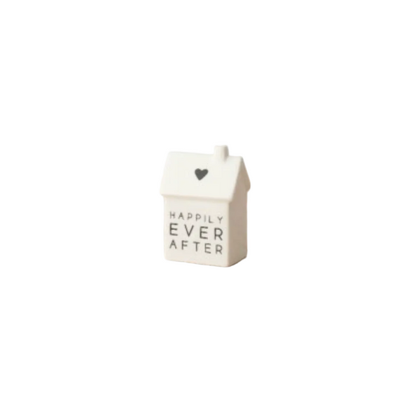 Small white ceramic house-shaped object with 'Happily Ever After' text on a white surface.
