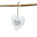 White heart-shaped hanging ornament with text on a branch against a light background