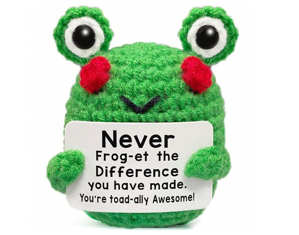 A green crocheted plush frog holding a white sign that reads, 'Never Frog-et the Difference you have made. You're toad-ally Awesome!' on a plain white background.