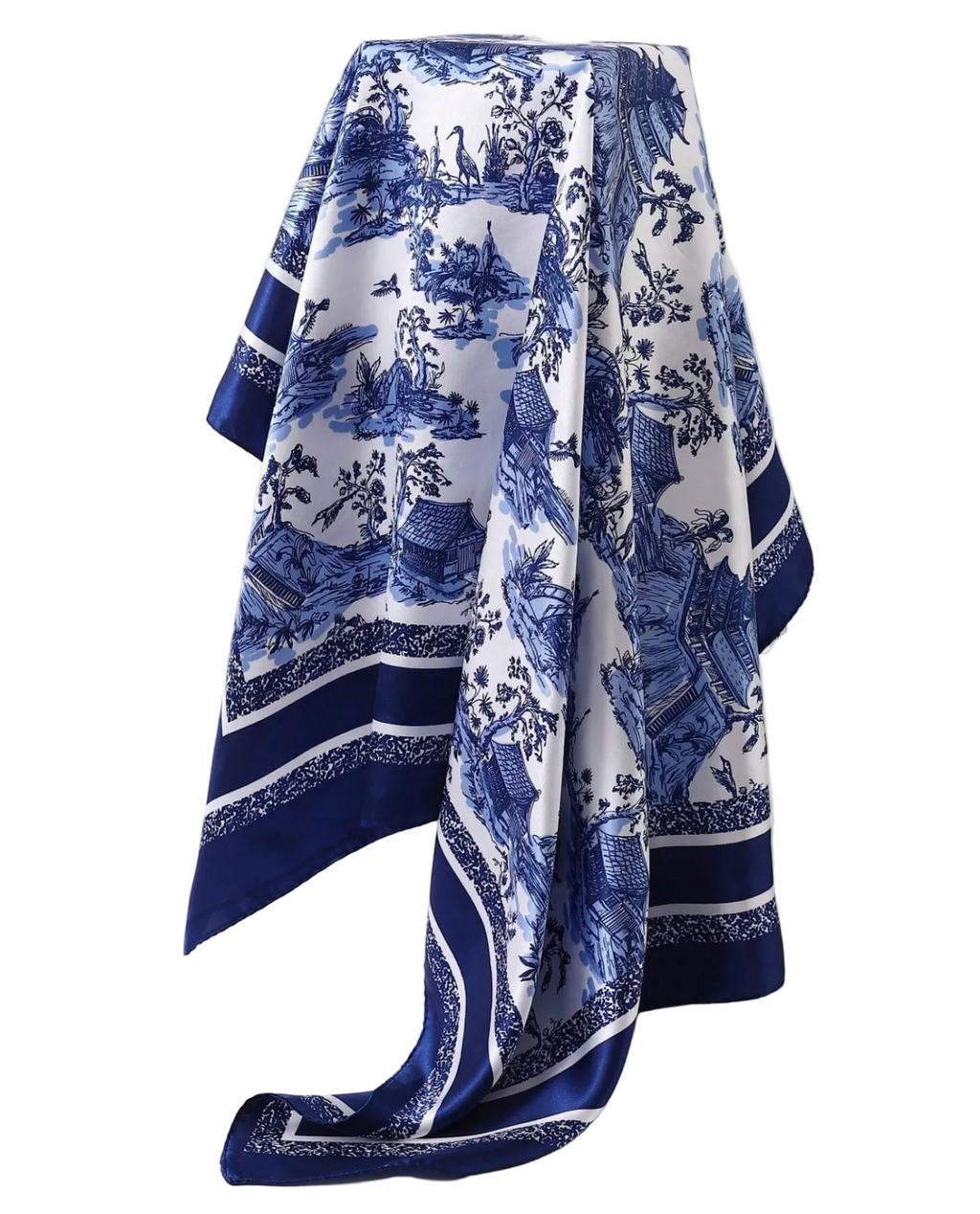 A white silk scarf with a classic blue toile print of figures, animals, and landscapes, draped elegantly on a white mannequin against a light gray background.