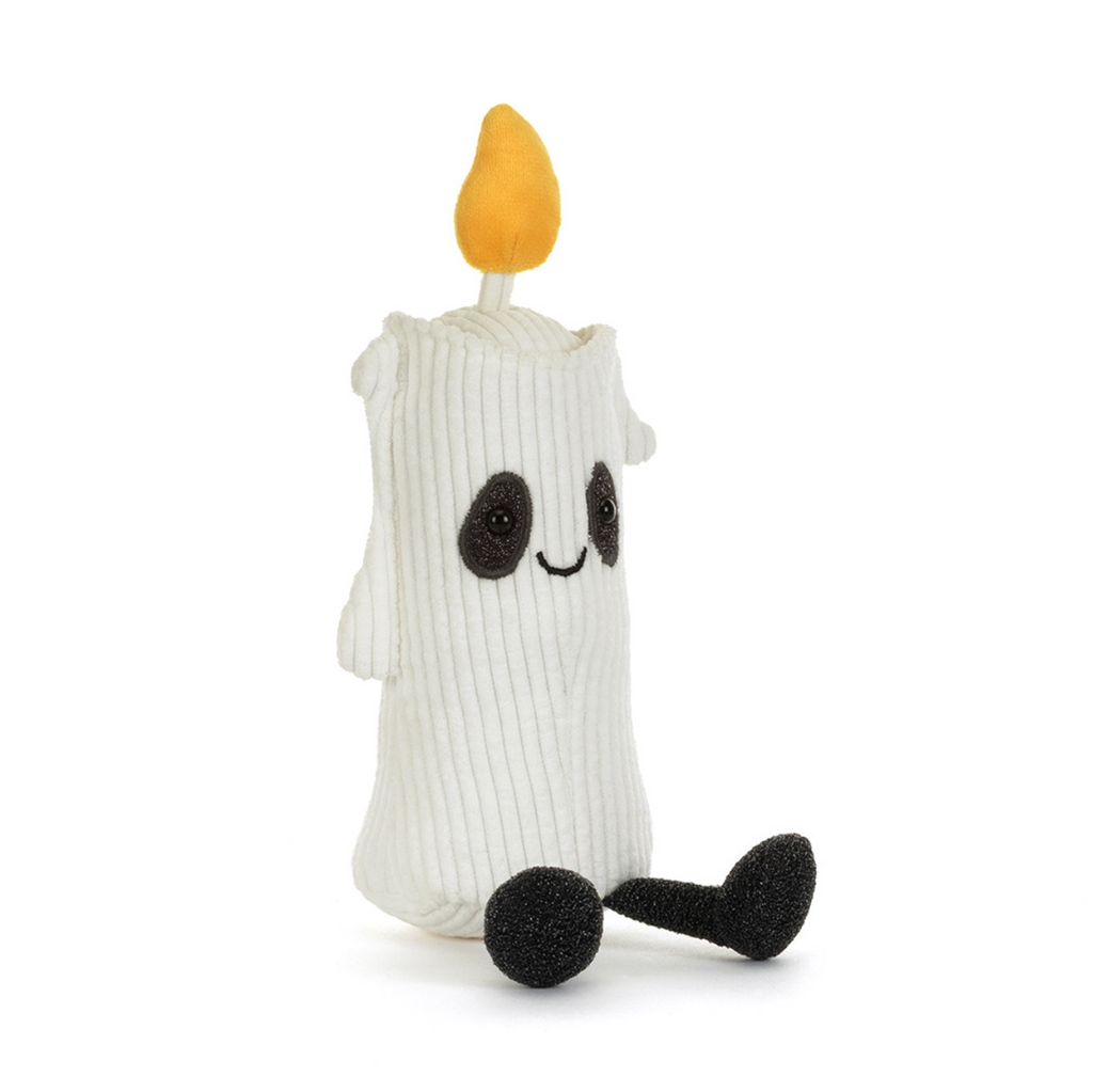 A white ribbed corduroy plush candle character toy with a yellow flame on top, black embroidered eyes and mouth, and black foam feet, photographed on a clean white background.