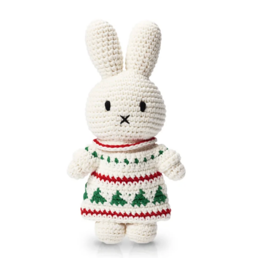 A crocheted bunny plush toy wearing a festive Christmas sweater with green trees and red patterns, set against a plain white background.