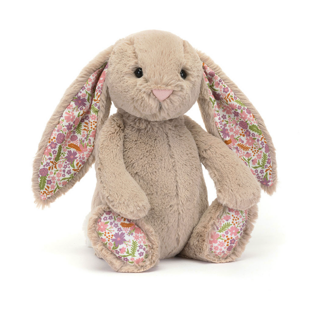 A plush stuffed bunny in warm beige with long floppy ears and floral-patterned inner ears, photographed on a clean white background.