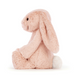 A plush stuffed bunny in a soft blush pink color with a white tail, sitting on a clean white background.