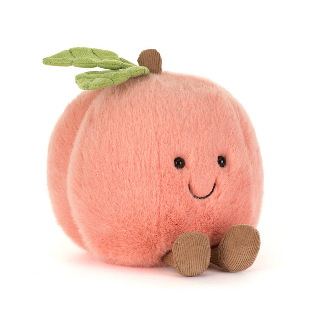 A plush peach toy with a soft pink body, green leaves on top, a small brown stem, embroidered black eyes and smile, and brown corduroy feet, photographed on a clean white background.