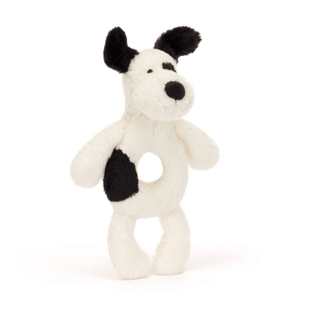 A plush dog-shaped baby teething toy with a white body, black ears, black nose, and a black patch on its side, set against a plain white background.