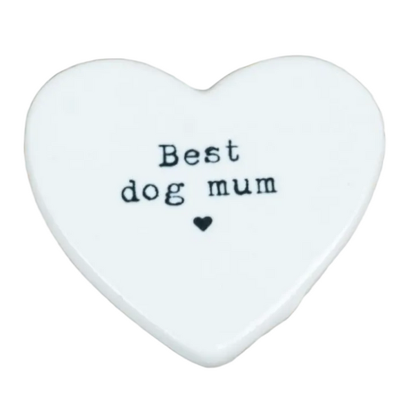 A white heart-shaped ceramic plaque with the text 'Best dog mum' and a small heart printed in black, displayed on a light-colored wooden surface.