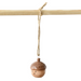 A small wooden acorn ornament with a smiling face hangs from a natural twine string tied to a light wood rod against a plain white background.
