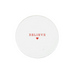 A round white ceramic coaster with the word 'BELIEVE' printed in red serif letters and a small red heart underneath, placed on a rustic white surface.