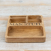 A rectangular wooden compartment tray engraved with the words 'MAN STUFF' in black lettering, placed on a light wood surface.