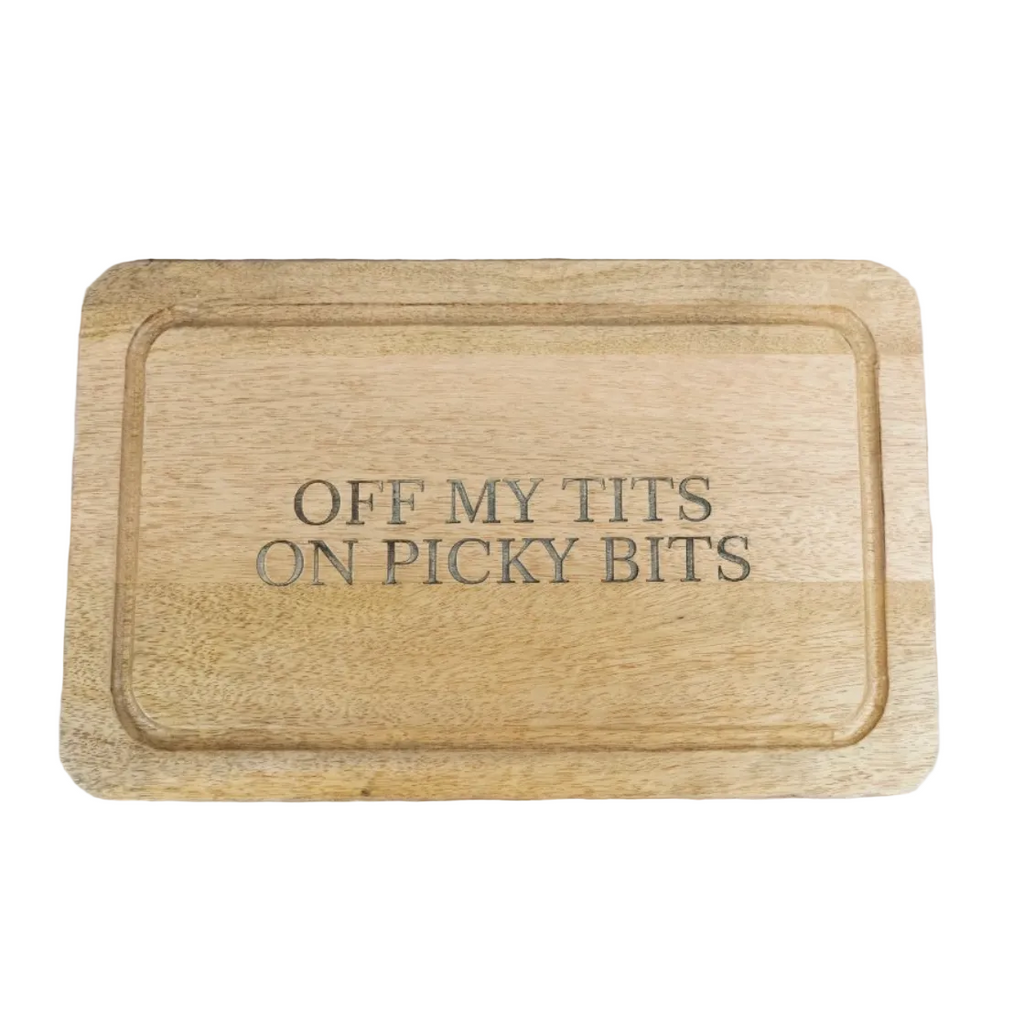 A rectangular wooden cutting board with rounded corners and a raised rim, featuring the engraved text 'OFF MY TITS ON PICKY BITS' in dark lettering.
