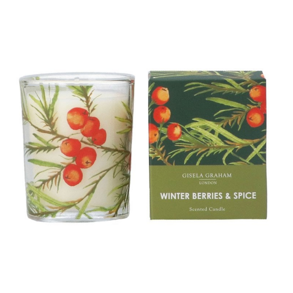 A scented candle in a clear glass jar with a winter berries and spice botanical print, shown next to its green and olive packaging box by Gisela Graham London.