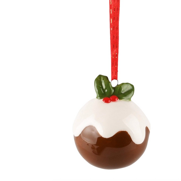 A Christmas pudding ornament shaped like a glossy brown pudding with white icing, a green holly leaf, and red berries, hanging from a red ribbon on a white background.