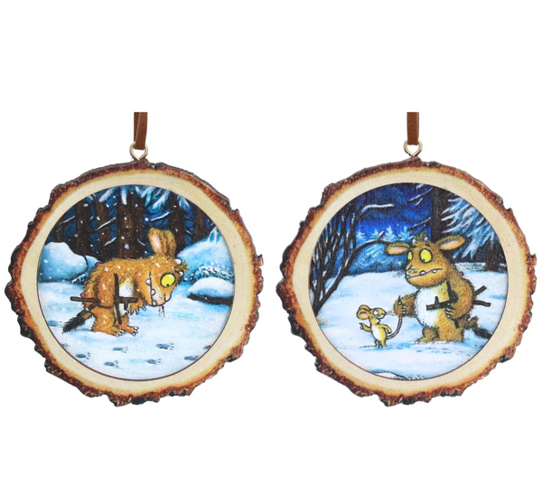Two round Christmas ornaments made from natural tree bark slices, each featuring a colorful winter illustration. One ornament shows a brown animal in a snowy forest, and the other shows a similar animal with a small yellow creature under a dark blue night sky.