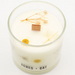 Candle in a glass jar with dried flowers and a wooden wick, branded 'Agnes + Cat'.