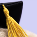 Close-up of a black graduation cap with a yellow tassel on a blurred background