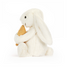White plush bunny holding a gold heart on a white background