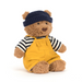 Stuffed teddy bear wearing a navy hat, striped shirt, and yellow overalls on a white background