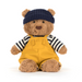 Teddy bear wearing a navy hat, striped shirt, and yellow overalls on a white background