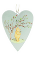 Heart-shaped hanging ornament featuring a painted scene of a yellow bear standing under a flowering tree with red blossoms on a pale blue-green background.