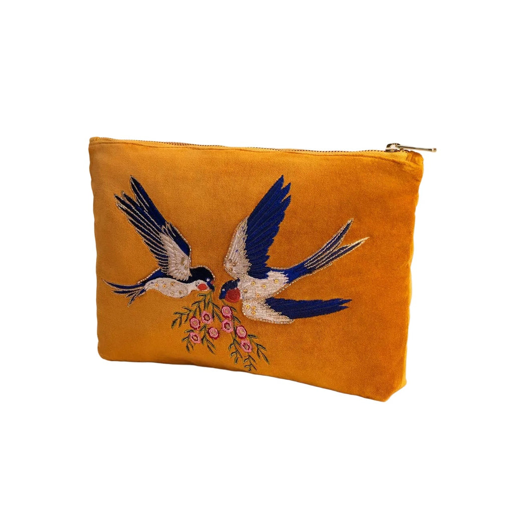 Mustard yellow pouch with embroidered design of birds and flowers on a white background