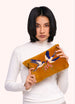 Woman holding a brown clutch with bird design on a white background
