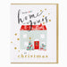 A festive Christmas greeting card with a gold border, featuring the text 'from our home to yours at christmas' in black and gold script. The center of the card is decorated with an illustration of a light blue house with a red polka-dot roof, a red front door, a green Christmas tree, and wrapped gifts, all on a white background.