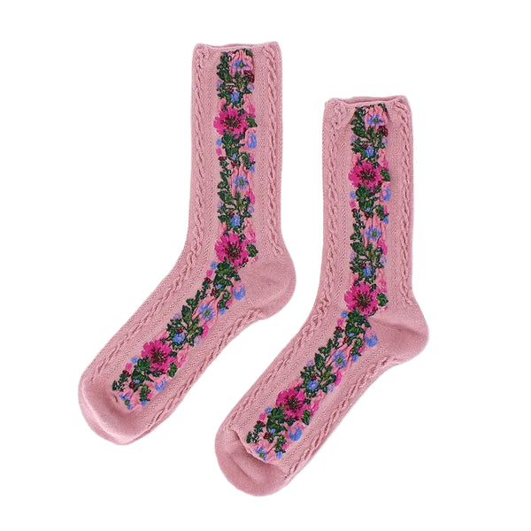 A pair of light pink crew socks with a vertical floral pattern in pink, purple, and green, featuring a decorative lace-like trim along the sides, shown on a light gray background.