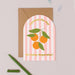 Greeting card with oranges and text 'Squeeze the day, Birthday Superstar!' on a striped background, with an envelope and pen.