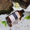 Bottle of ancient wisdom oil with natural elements on a reflective surface