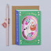 Mrs Best Paper Co. book-shaped new baby card with gold foil stork illustration and kraft envelope on grey background