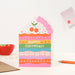 Mrs Best Paper Co. die-cut birthday card shaped like a rainbow cake slice with sprinkles, hearts, and cherry topper.