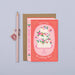 Mrs Best Paper Co. book-shaped wedding card with a tiered cake illustration, gold foil details, and kraft envelope.
