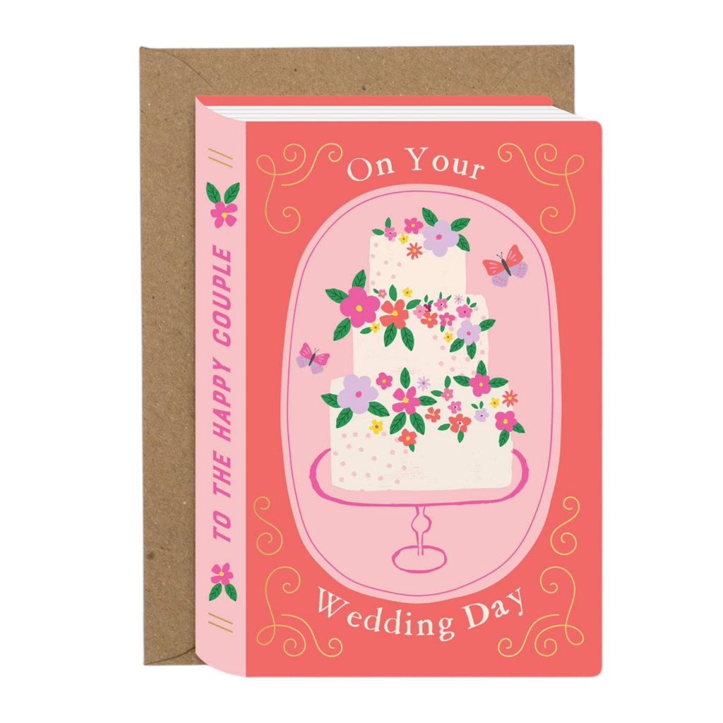 Mrs Best Paper Co. wedding card shaped like a book with a tiered cake illustration, gold foil, and kraft envelope.