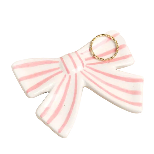 Ceramic bow-shaped object with pink stripes on a beige background