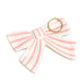 Ceramic bow-shaped object with pink stripes on a beige background